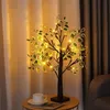 A decorative artificial tree with LED lights sits on a small table next to a cup of coffee, with curtains in the background. Produktbild-Vorschau