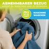 A person is putting a blue blanket into a washing machine. Produktbild-Vorschau