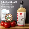 A bottle of LEINOS Naturfarben Arbeitsplattenöl is shown next to fresh tomatoes and a certificate, suggesting its use in kitchens and its food-safe properties. Produktbild-Vorschau
