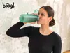 A young woman drinks from a green water bottle. Produktbild-Vorschau