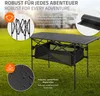 A black camping table is set up on a grassy field, with promotional text and graphics surrounding it. Produktbild-Vorschau
