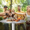 A group of friends toasting with drinks and food on a table in an outdoor setting. Náhled obrázku produktu