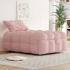 A pink upholstered chaise lounge with a single pillow sits on a patterned rug in a well-lit room. A potted plant is visible in the background. Anteprima dell’immagine prodotto