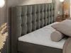 A close-up view of a bed with a tufted headboard, showing the mattress and pillows. Produktbild-Vorschau