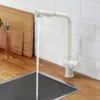 A white kitchen faucet with water running into a stainless steel sink, set against a white subway tile backsplash and a wooden countertop. Produktbild-Vorschau