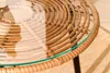 Close-up of a round wicker table with a glass top, showing the texture and weave of the material. Produktbild-Vorschau