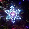 A close-up of a snowflake ornament on a Christmas tree with colorful lights. Voir les images du produit