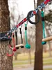 A slackline with various attachments for a ninja warrior course, set up between two trees. Produktbild-Vorschau