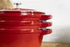 A close-up view of three stacked red Dutch ovens. Produktbild-Vorschau