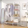 A white metal and wood garment rack with clothes hanging on it and shelves for storage, next to a full-length mirror and a small cabinet. Produktbild-Vorschau
