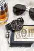 A collection of men's accessories including a watch, sunglasses, a flask, and a bottle of liquor, arranged on a white furry surface. Anteprima dell’immagine prodotto