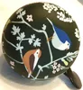 A close-up shot of a bicycle bell with a dark green background and a nature-themed illustration. Produktbild-Vorschau