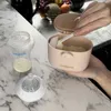 A person is using a portable milk powder container to scoop powder into a baby bottle. Produktbild-Vorschau