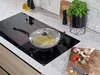 A cooking scene with a frying pan on a stovetop, surrounded by ingredients. Produktbild-Vorschau