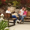 Three people sitting on a park bench in an outdoor setting with rocks and foliage. Podgląd zdjęcia produktu