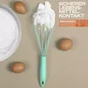 A whisk with whipped egg whites, eggs, and a bowl of whipped egg whites are arranged on a beige surface. Anteprima dell’immagine prodotto