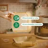 A hand holding air fryer liners next to an air fryer and a stack of liners. Produktbild-Vorschau