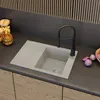 A modern kitchen sink with a black faucet, set against a dark backsplash and wooden cabinets. There are some jars of food and fruit on the counter. Podgląd zdjęcia produktu