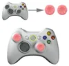 A white Xbox 360 controller with pink thumb grips and a diagram showing the thumb grips being applied. Produktbild-Vorschau