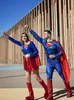 Two people in Superman costumes posing in front of a modern building. Produktbild-Vorschau
