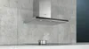 A modern kitchen with a stainless steel range hood mounted on a concrete tile backsplash. Voir les images du produit