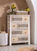A boho-chic style wooden chest of drawers with macrame detailing on some drawers, placed in a room with wooden walls and a light-colored floor. Voir les images du produit