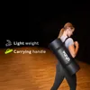 A woman is carrying a rolled-up yoga mat over her shoulder in a studio or gym setting. Podgląd zdjęcia produktu