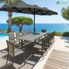 An outdoor dining set with a large umbrella by the sea. Produktbild-Vorschau