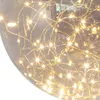 A close-up view of a clear glass sphere containing a string of small, warm white LED lights. Produktbild-Vorschau
