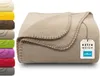 A folded beige fleece blanket with a tag attached. Produktbild-Vorschau