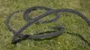 A black hose with white speckles lies coiled on green grass. Produktbild-Vorschau