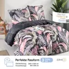 A bed with a floral duvet and pillows, styled with a small table and plant. Produktbild-Vorschau