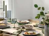 A beautifully set dining table with plates of food, glasses, and candles. Produktbild-Vorschau