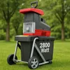 A garden shredder is shown outdoors on a grassy lawn with trees in the background. Produktbild-Vorschau
