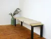 A bench with beige seat cushions and black legs is placed against a white wall, with a green vase and dried flowers to the left. Anteprima dell’immagine prodotto
