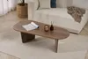 A modern living room scene with a coffee table in the foreground and a couch in the background. Produktbild-Vorschau