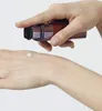 A hand is dispensing a small amount of cream from a red and silver pump bottle onto another hand. Produktbild-Vorschau
