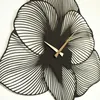 A close-up view of a black metal wall clock designed to look like a flower. Produktbild-Vorschau
