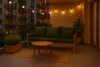 A balcony at dusk with a sofa, coffee table, and string lights. Náhľad obrázku produktu