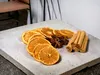 Dried orange slices, star anise, and cinnamon sticks arranged on a concrete slab. Podgląd zdjęcia produktu