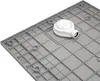 The underside of a grey shower tray with a white drain assembly attached. Produktbild-Vorschau