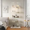 A glass display cabinet filled with various decorative items and toiletries, placed in a bedroom setting next to a bed and a round side table. Náhled obrázku produktu
