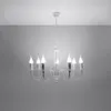 A white chandelier with seven candle-shaped bulbs hangs from a white ceiling against a light gray wall. Voir les images du produit
