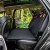 The interior of a car with a dog seat cover installed on the back seat, with trees and foliage visible through the open door and windows. Produktbild-Vorschau