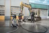A man is pressure washing a construction vehicle with a Kärcher pressure washer. Produktbild-Vorschau