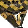 A close-up view of the handle and part of the head of a black and gold padel racket. Anteprima dell’immagine prodotto