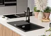 A modern kitchen sink with a black granite basin and a black faucet, set on a white countertop. Produktbild-Vorschau
