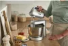 A person is using a hand mixer in a kitchen setting. Produktbild-Vorschau