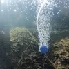 Underwater view of a blue aeration stone and bubbles rising from a tube in a pond or aquarium with mossy rocks. Produktbild-Vorschau