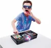 A young boy wearing sunglasses and a blue t-shirt is enthusiastically using a DJ mixing controller on a white table. Náhľad obrázku produktu